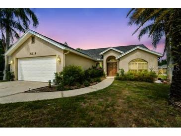 Charming single-story home with a manicured lawn, inviting curb appeal, and attached two-car garage at 5112 Parkway Blvd, Land O Lakes, FL 34639
