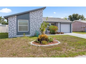 Charming home featuring a unique stone accent wall, well-maintained lawn, and lovely front garden at 10213 Westport Ct, Tampa, FL 33615