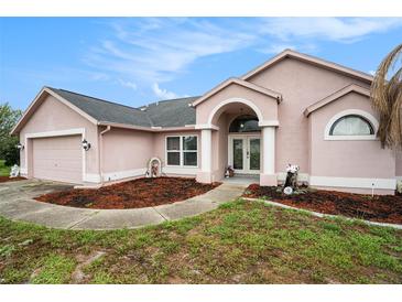 Charming one-story home featuring an arched entryway, a two-car garage, and beautifully landscaped front yard at 12214 Buckingham Way, Spring Hill, FL 34609