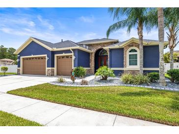 Stunning home with a beautifully landscaped yard, complemented by a two-car garage and elegant stone accents at 1741 Beaconsfield Dr, Wesley Chapel, FL 33543