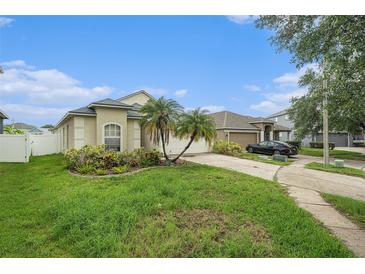 Single-story home featuring a neutral palette, well-manicured landscaping, and an attached two-car garage at 8217 Canterbury Lake Blvd, Tampa, FL 33619