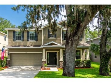 Two-story home with a two-car garage, neutral siding, black shutters and a lovely lawn at 12208 Mcmullen Loop, Riverview, FL 33569
