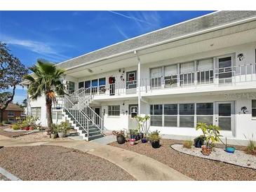 Inviting two-story condo featuring white exterior and well-maintained landscaping with a palm tree and gravel walkway at 1221 Drew St # C2, Clearwater, FL 33755