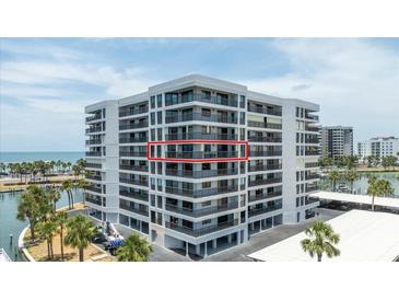 Modern condo building showcasing sleek design and waterfront views, accentuated by palm trees and sunny skies at 1651 Sand Key Estates Ct # 54, Clearwater Beach, FL 33767