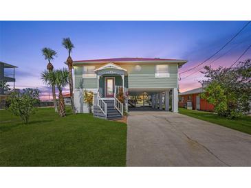 Charming raised beach house with a red roof, palm trees, and a spacious driveway at 4137 Des Prez Ct, Hernando Beach, FL 34607