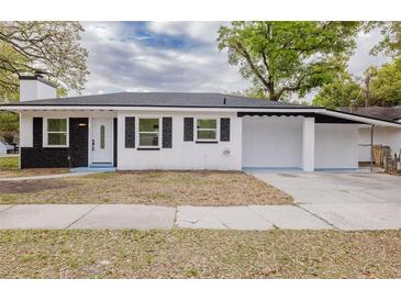 Charming single-story home with a black-and-white exterior, complemented by an attached carport and well-manicured lawn at 5801 N 17Th St, Tampa, FL 33610