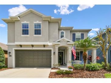 Charming two-story home featuring a gray facade, landscaped yard, and an attached two-car garage at 6214 Windship Ct, Tampa, FL 33647