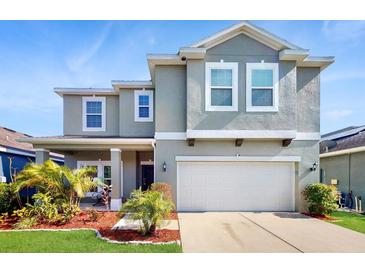 Beautiful two-story home featuring a two-car garage, manicured lawn, and lovely landscaping at 8111 Brickleton Woods Ave, Gibsonton, FL 33534