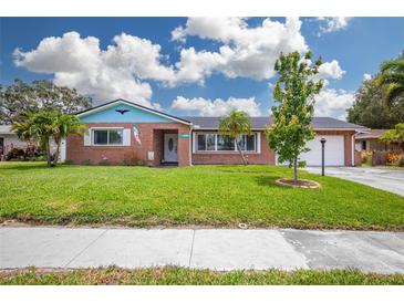 Charming brick home with a well-manicured lawn, vibrant foliage, and a two-car garage at 13296 88Th N Ave, Seminole, FL 33776