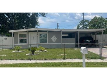 Charming single-story home with a carport, well-maintained lawn, and a white picket fence at 1335 Waikiki Way, Tampa, FL 33619