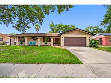 Charming one-story home featuring a brown two-car garage, well-maintained lawn, and inviting front porch area at 2329 Carrie Ct, Dunedin, FL 34698