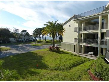 Well-maintained three-story building with lush green lawn, palm tree, and partial water view at 2700 Bayshore Blvd # 5307, Dunedin, FL 34698