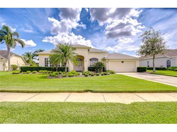 Charming single-story home with a well-manicured lawn and lush, tropical landscaping at 4304 Place Le Manes, Lutz, FL 33558
