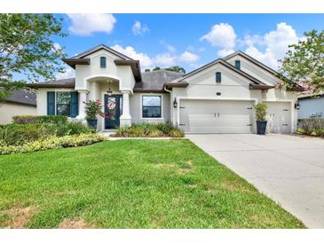 Charming single-story home with a manicured lawn, flowering shrubs, and a three car garage at 679 Challice Dr, Spring Hill, FL 34609
