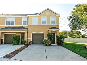 Two-story townhome featuring a one-car garage and a well-maintained front yard with green bushes at 6940 47Th N Way, Pinellas Park, FL 33781