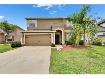 Charming two-story home featuring a well-manicured lawn, arched front door, and a spacious two-car garage at 12316 Streambed Dr, Riverview, FL 33579