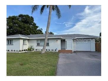 Charming single-story home with a well-maintained lawn, a palm tree and a driveway at 3118 Adrian Ave, Largo, FL 33774