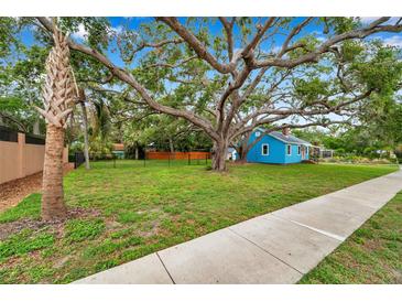 Charming blue cottage with a lush lawn and mature trees in a desirable neighborhood at 320 Broadway, Dunedin, FL 34698