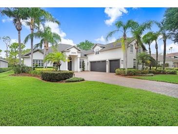 Beautiful home with lush landscaping, palm trees, and a circular brick driveway at 3519 Old Course Ln, Valrico, FL 33596