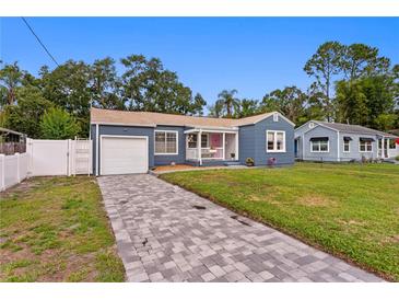 Charming blue home featuring an attached garage, a welcoming front porch, and a beautifully paved driveway at 4012 N Munro St, Tampa, FL 33603