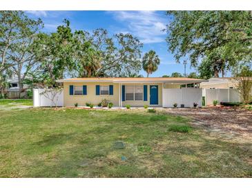 Charming yellow home with blue shutters, a well-maintained lawn and welcoming curb appeal on a sunny day at 4714 W Vasconia St, Tampa, FL 33629