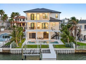 Stunning waterfront home featuring a private pool, dock, and multiple balconies perfect for enjoying the coastal views at 820 Bay Point Dr, Madeira Beach, FL 33708