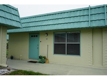 Charming condo with turquoise accents, including door and trim, creating a vibrant and welcoming entrance at 101 Cambridge Trl # 205, Sun City Center, FL 33573