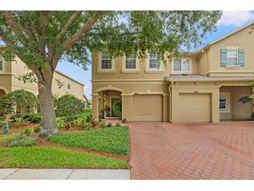 Charming townhome with a brick driveway, mature landscaping, and an attached two-car garage at 17527 Stinchar Dr, Land O Lakes, FL 34638