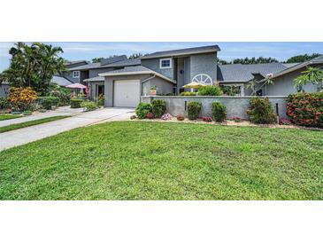 Charming townhome with lush front lawn, flowering shrubs, and an attached single car garage at 184 Hunter Ct, Palm Harbor, FL 34684