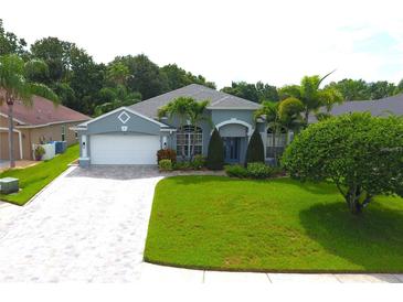 Charming single-story home with a paver driveway, lush lawn, and manicured landscaping at 1842 Ridgelake Ct, Wesley Chapel, FL 33543