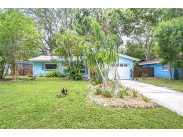 Charming blue home with lush landscaping and a well-manicured lawn, set among mature trees, creating a tranquil oasis at 2051 Indigo Dr, Clearwater, FL 33763