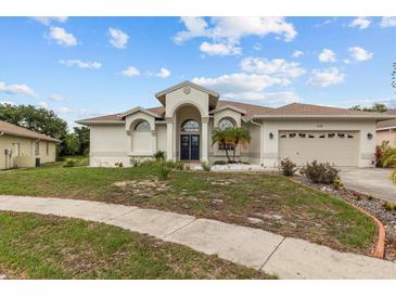Stunning single-Gathering home with a well-manicured lawn, neutral color palette, and arched entryway at 3138 Deergrass Ct, Holiday, FL 34691
