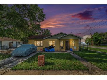Charming bungalow with a well-maintained lawn and covered car at sunset at 3201 E Mcberry St, Tampa, FL 33610