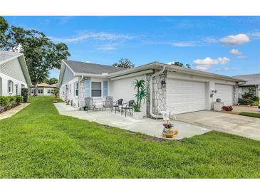 Charming home exterior featuring a cozy patio area, lush green lawn, and attached garage at 3271 Mcmath Dr, Palm Harbor, FL 34684