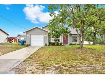 Charming gray home with a well-manicured lawn, mature trees, and a welcoming red front door at 4342 Candler Ave, Spring Hill, FL 34609