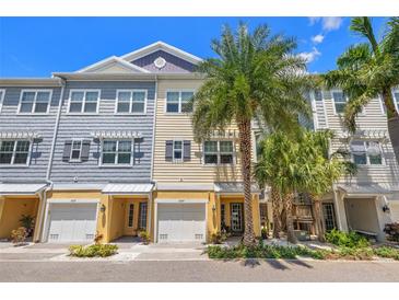Charming townhomes boast a bright exterior, complemented by lush palm trees and beautiful landscaping at 6049 Moorings S Dr, St Petersburg, FL 33712