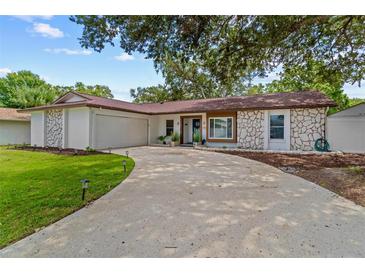 Charming single-story home with a well-manicured lawn, stone accents and a curved driveway at 2824 Paddock Dr, Palm Harbor, FL 34684
