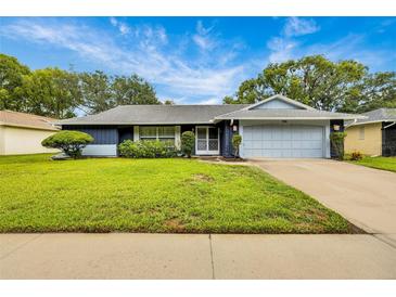 Charming single-story home with well-maintained lawn, mature trees, and an attached two car garage at 7708 Fairlawn Dr, Hudson, FL 34667