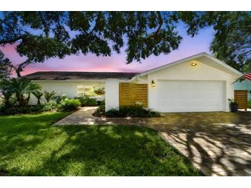 Charming single Gathering home with manicured lawn and a two car garage with a brick walkway at 1286 Stony Brook Ln, Dunedin, FL 34698