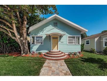 Charming bungalow featuring a manicured lawn, mature tree, and inviting yellow door at 1525 38Th N Ave, St Petersburg, FL 33704