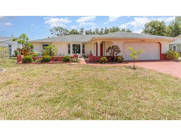 Charming single-story home with well-maintained front yard and inviting red accents on the driveway and entrance at 1839 Neptune Dr, Englewood, FL 34223