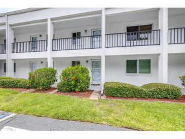 Inviting condo exterior with white facade, black railings, and lush landscaping at 2060 Marilyn St # 114, Clearwater, FL 33765