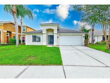 Charming single-story home with a well-manicured lawn, arched entryway, and two-car garage at 25729 Aldus Dr, Land O Lakes, FL 34639