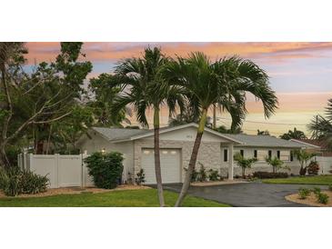Charming home with stone accents, palm trees, manicured lawn, driveway, and an attached two-car garage at 6913 Grande Vista S Way, St Petersburg, FL 33707