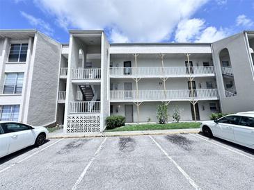 Condominium building with white facade, outdoor stairwell, and parking lot in front at 2625 State Road 590 # 1012, Clearwater, FL 33759