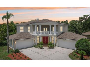 Elegant two-story home featuring a grand entrance with columns, balcony, and attached two-car garages at 3062 Sutton Woods Dr, Plant City, FL 33566