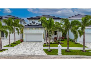 Beautiful two-story home with lush landscaping, a patterned driveway, and a white three-car garage at 6528 Simone Shores Cir, Apollo Beach, FL 33572