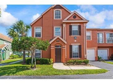 Charming two-story townhome featuring a well-manicured lawn and vibrant landscaping at 9842 Lake Chase Island Way, Tampa, FL 33626