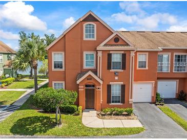 Charming two-story townhome featuring an attached garage and landscaped front yard with a beautiful blue sky backdrop at 9842 Lake Chase Island Way, Tampa, FL 33626