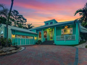 Beautiful two-story home with a vibrant exterior paint, brick driveway, and lush tropical landscaping at 1217 N Florida Ave, Tarpon Springs, FL 34689